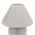 A close-up of the pleated fabric lampshade atop a floral globe lamp.