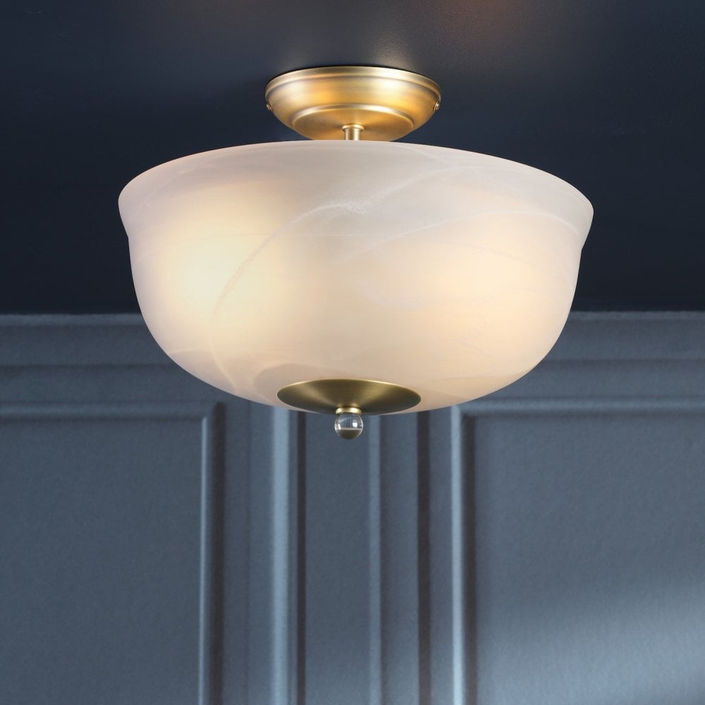 An illuminated semi-flush ceiling light with a brass base and a white marbled glass shade.