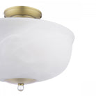 Close-up of a semi-flush ceiling light with a brass base and a white marbled glass shade.
