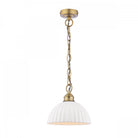 An ivory ribbed ceramic dome pendant light with a brass chain on a white background.