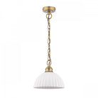 A white ribbed ceramic dome pendant light with a brass chain on a white background.