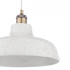 Detailed view of the white textured surface and brass fittings of the pendant light.