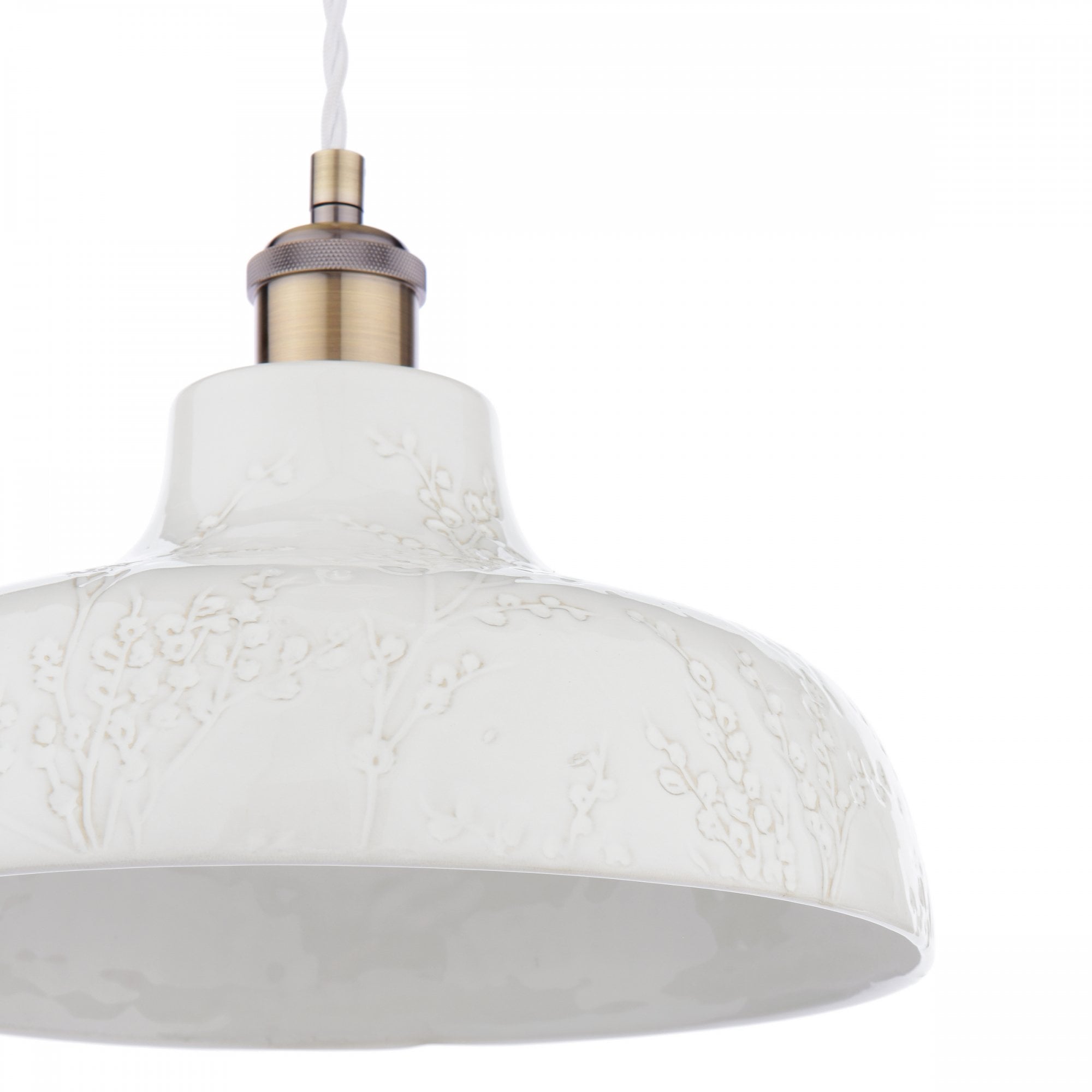 Detailed view of the white textured surface and brass fittings of the pendant light.