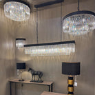 Multiple chandeliers with black frames and crystal rods in a display room.