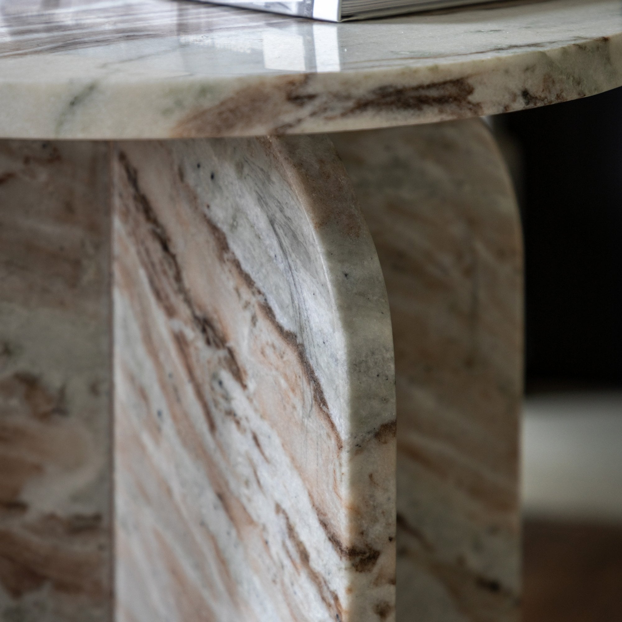 Close-up of the arched marble base and round tabletop with book.
