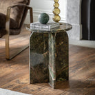 Green marble side table with rounded base in a living room next to a brown armchair.