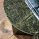 Close-up of a green marble tabletop with natural reddish-brown veins, holding a book.