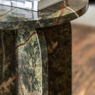 Detail of the green marble side table, showing the rounded base and tabletop edge.
