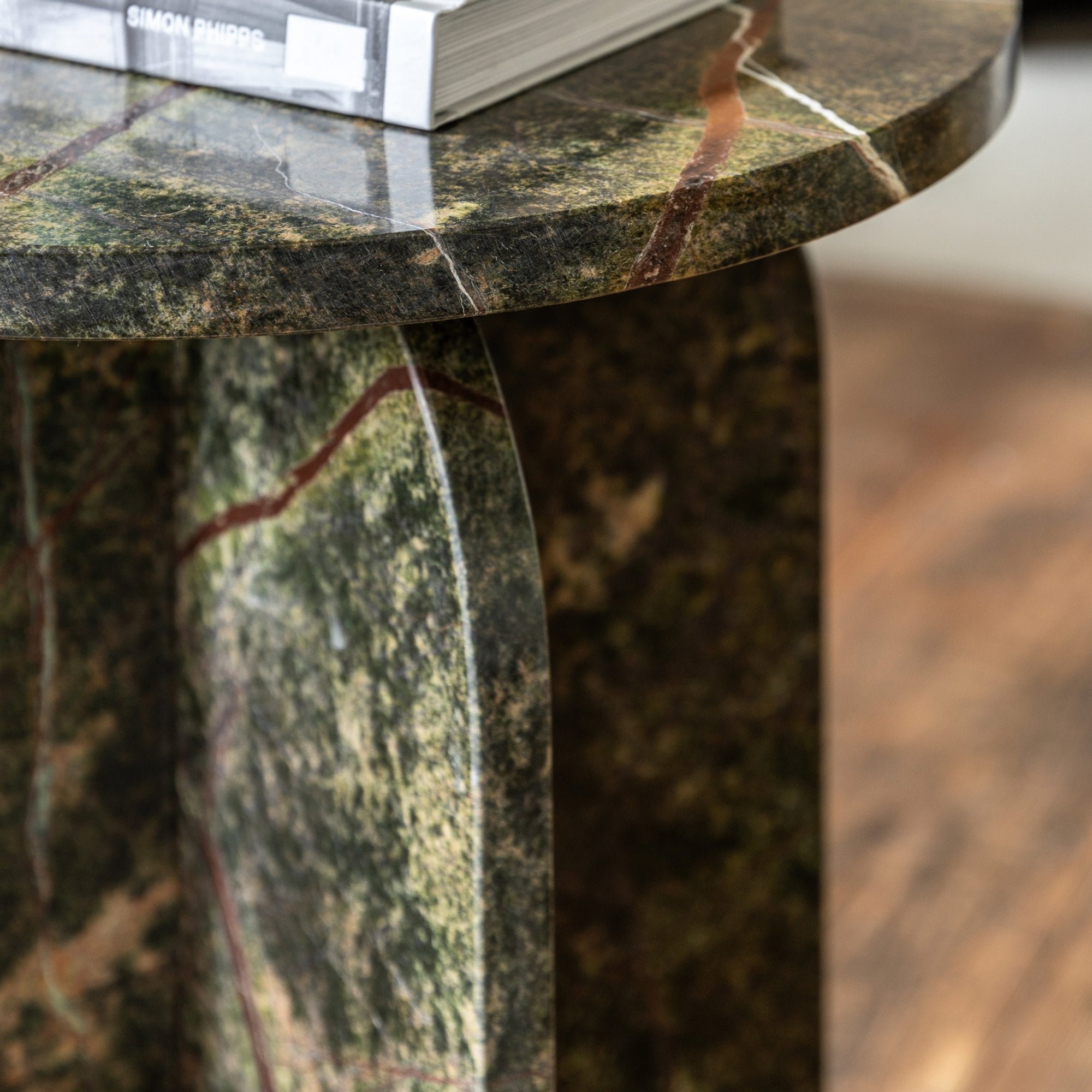 Detail of the green marble side table, showing the rounded base and tabletop edge.