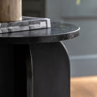 A side view of the black marble side table, highlighting its arched base design.