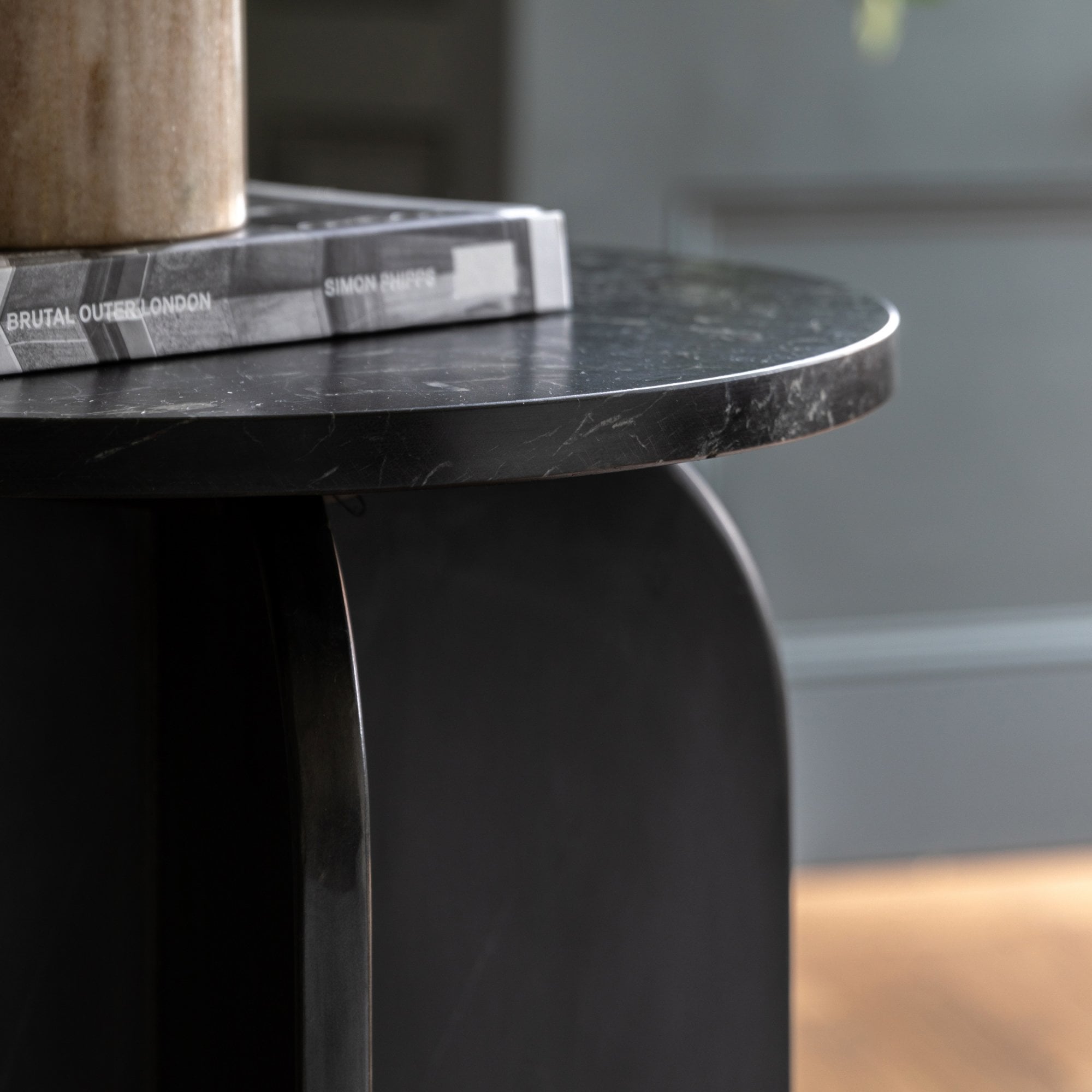 A side view of the black marble side table, highlighting its arched base design.