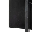 Close-up of the black marble side table's arched base with white veining.
