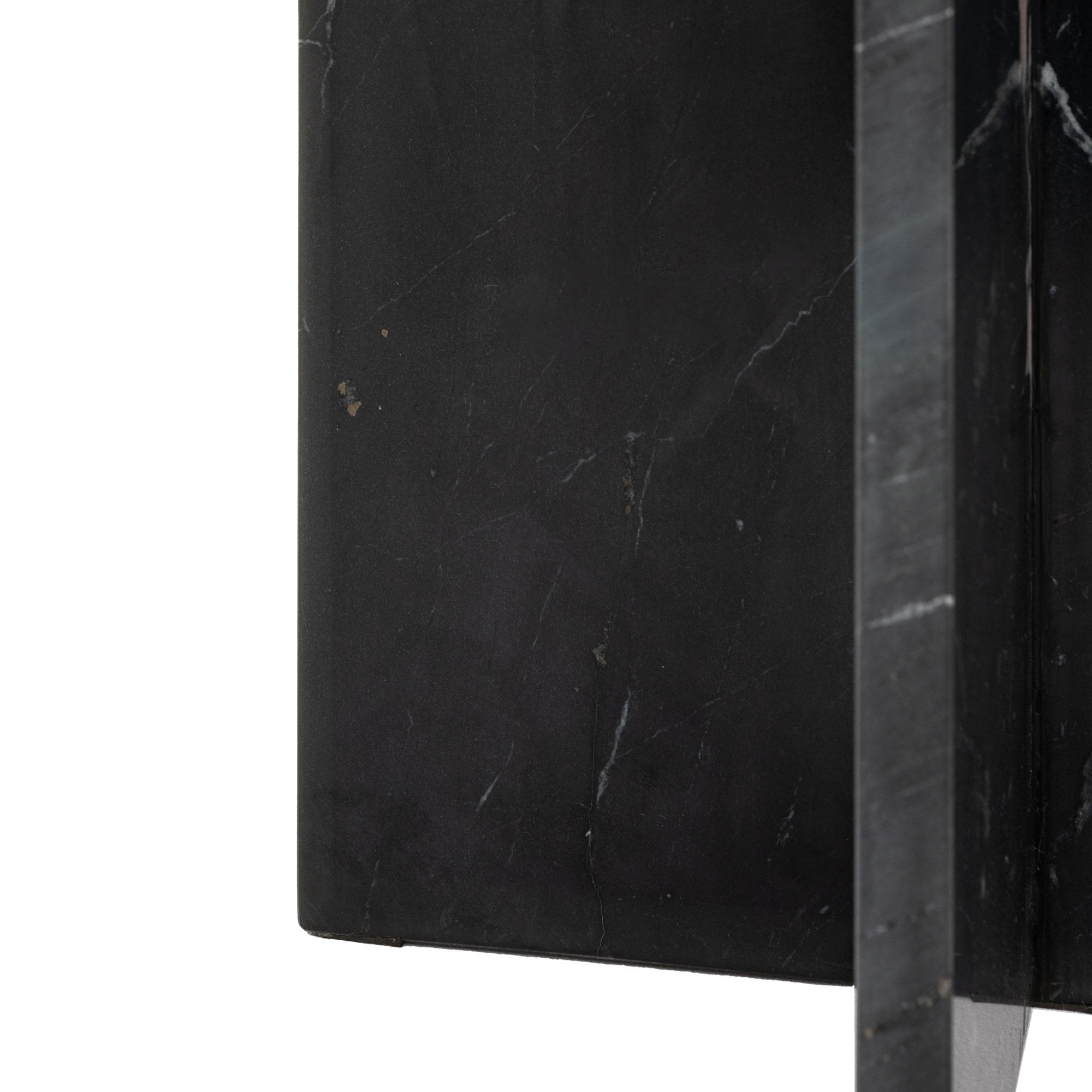 Close-up of the black marble side table's arched base with white veining.
