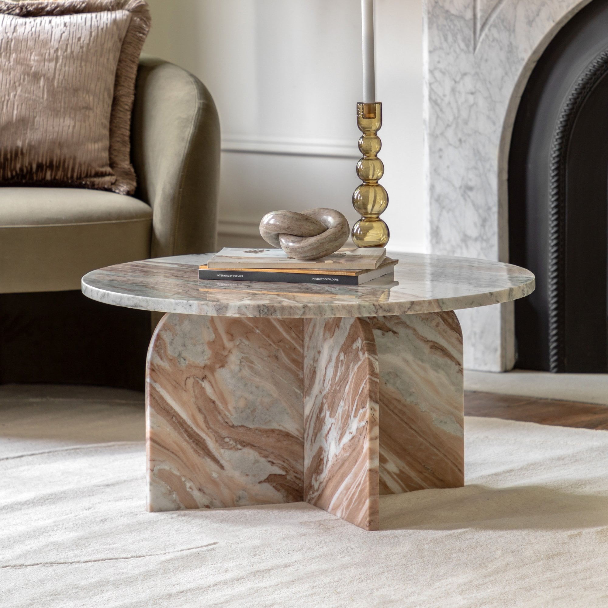 A round marble coffee table with a unique base, styled in a living room.