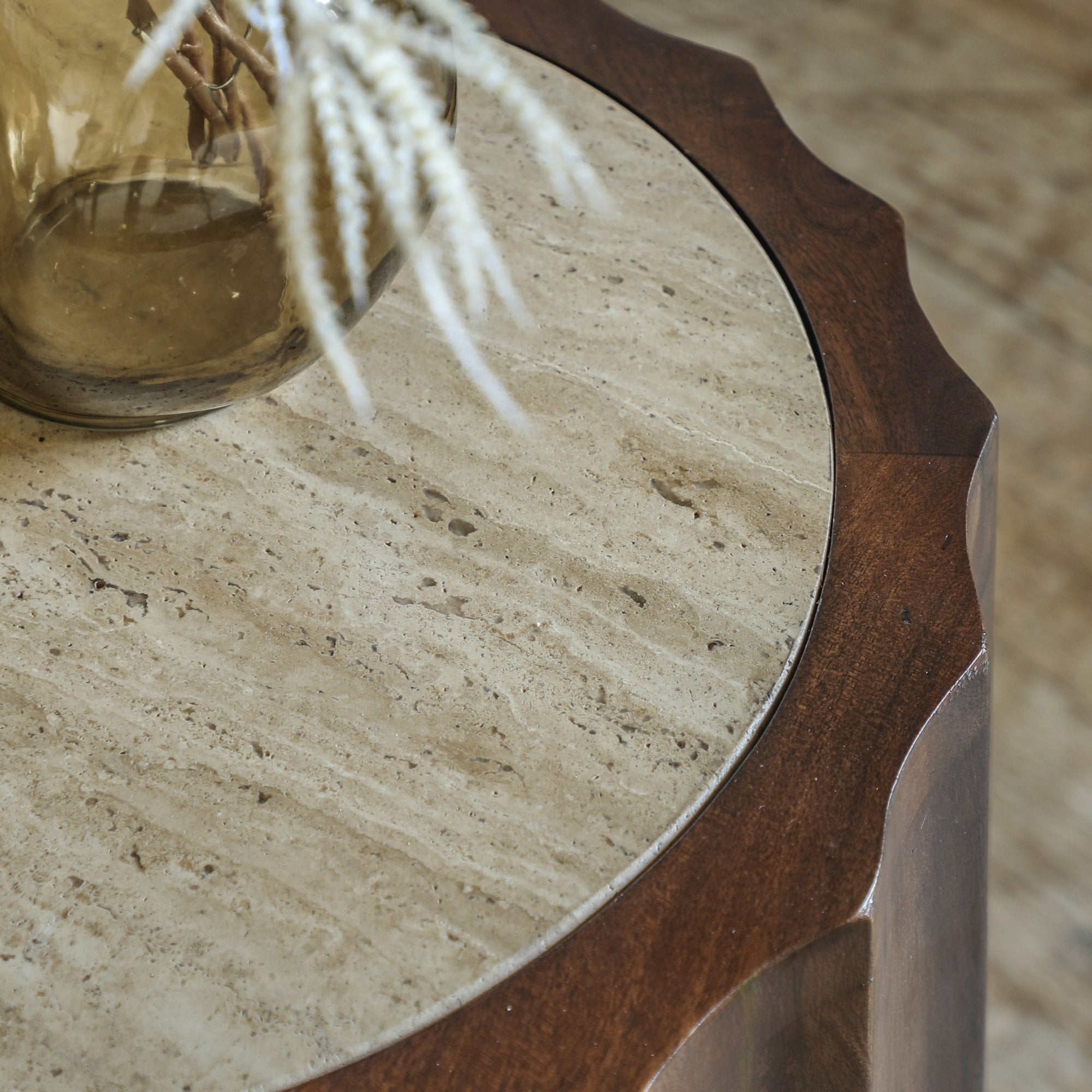A close-up of the light, textured stone top of a round wooden side table.