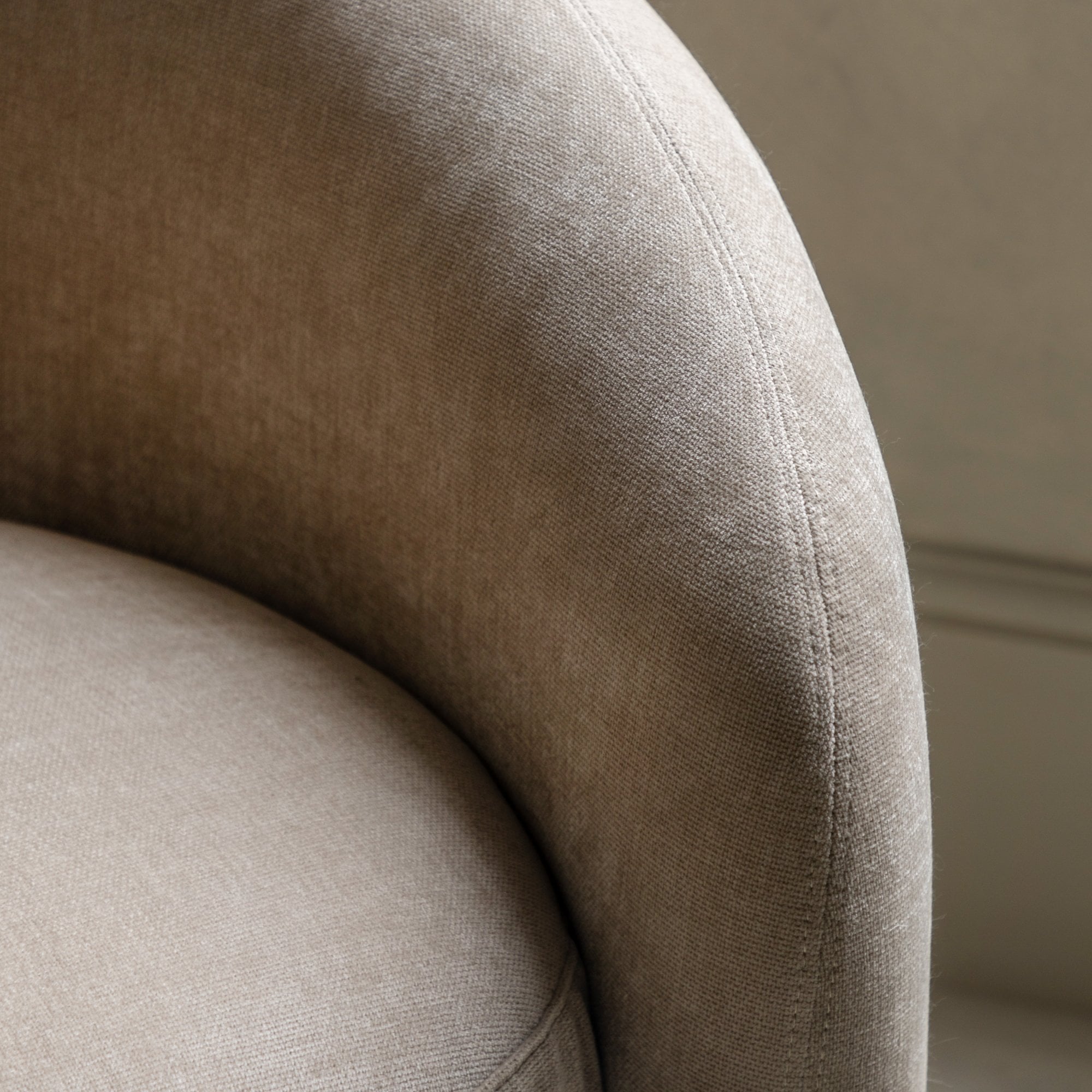 Detailed close-up of the beige sofa's textured fabric and stitching on an armrest.
