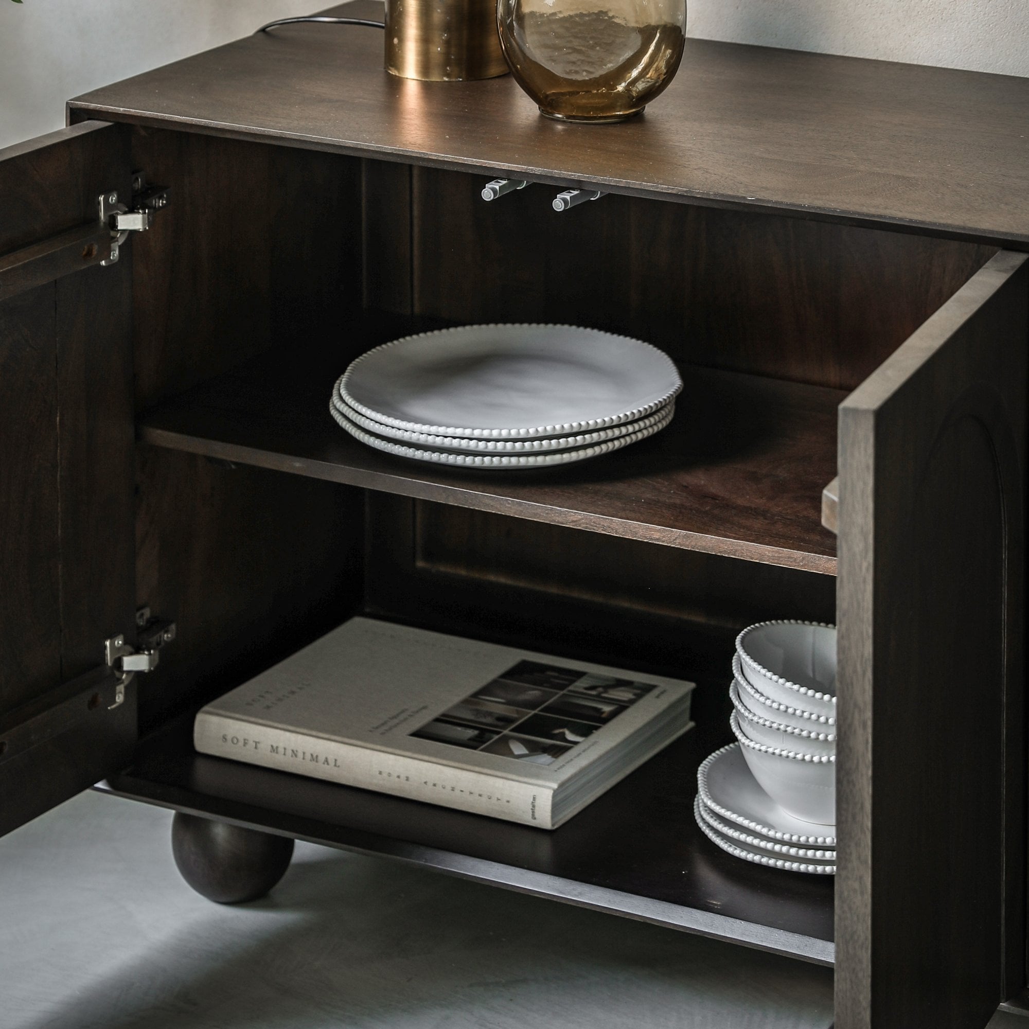 Interior view of the cabinet with plates and a book on shelves.