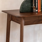 Close-up of the smooth, dark wood surface of the desk with subtle grain details.