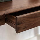 An open desk drawer showcasing the rich wood grain and precise craftsmanship.
