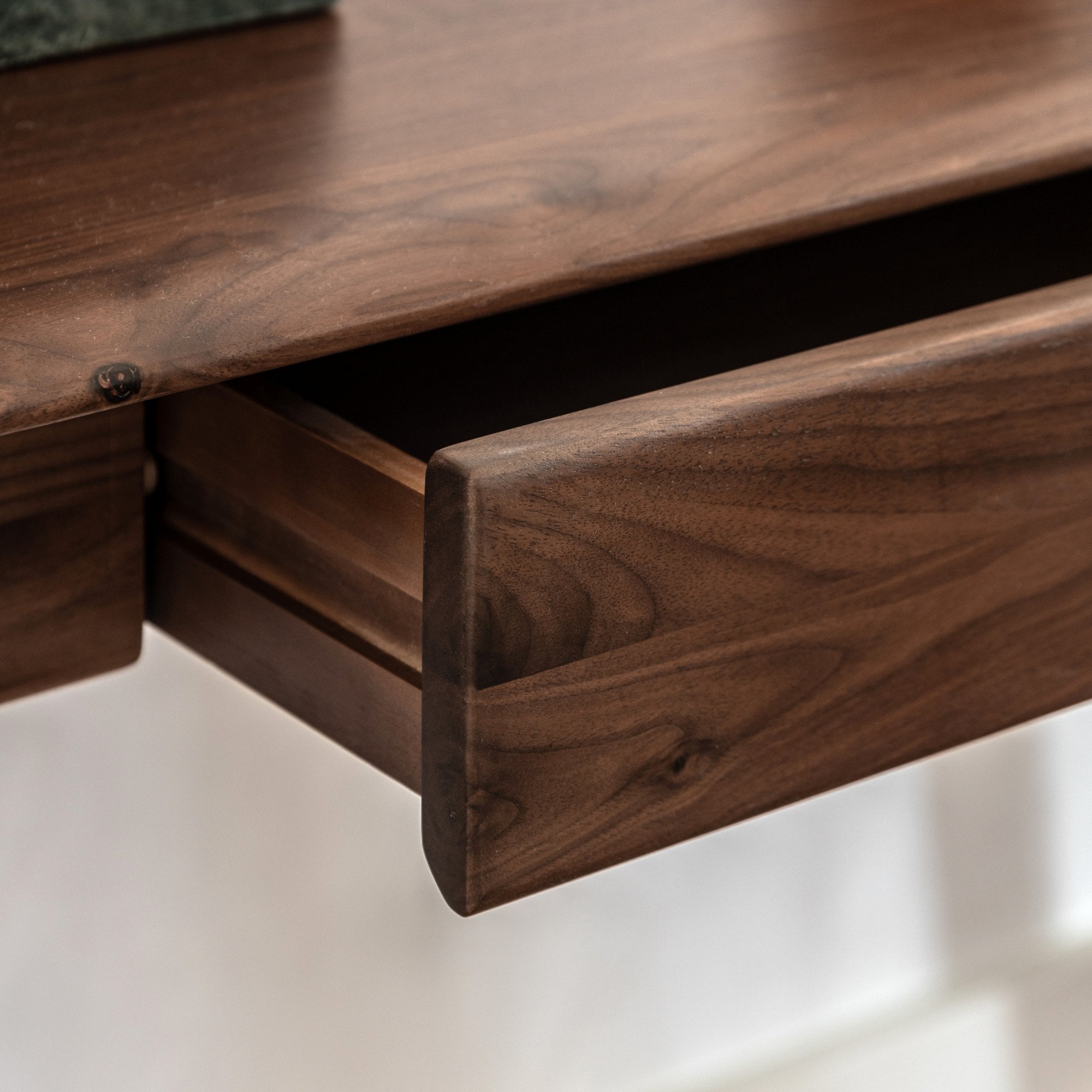 An open desk drawer showcasing the rich wood grain and precise craftsmanship.