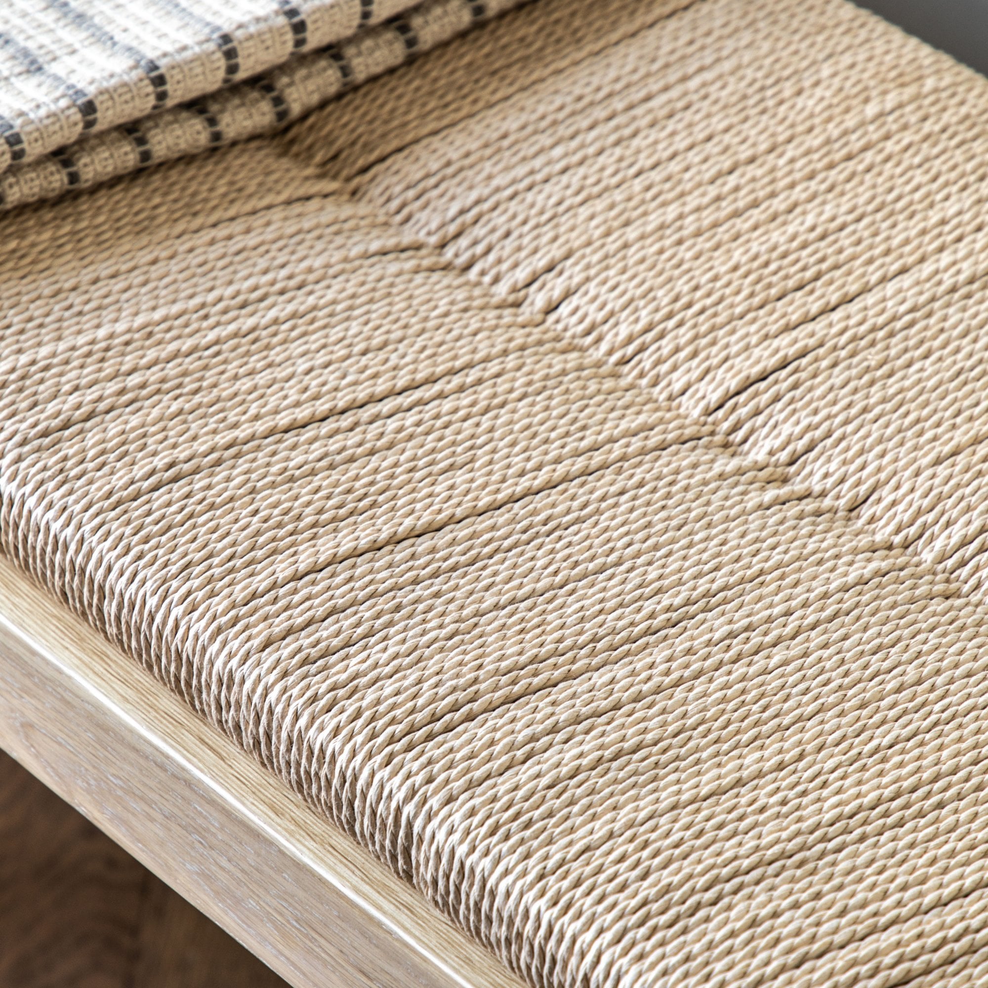 Close-up of the woven texture of the bench seat with a blanket partially visible.