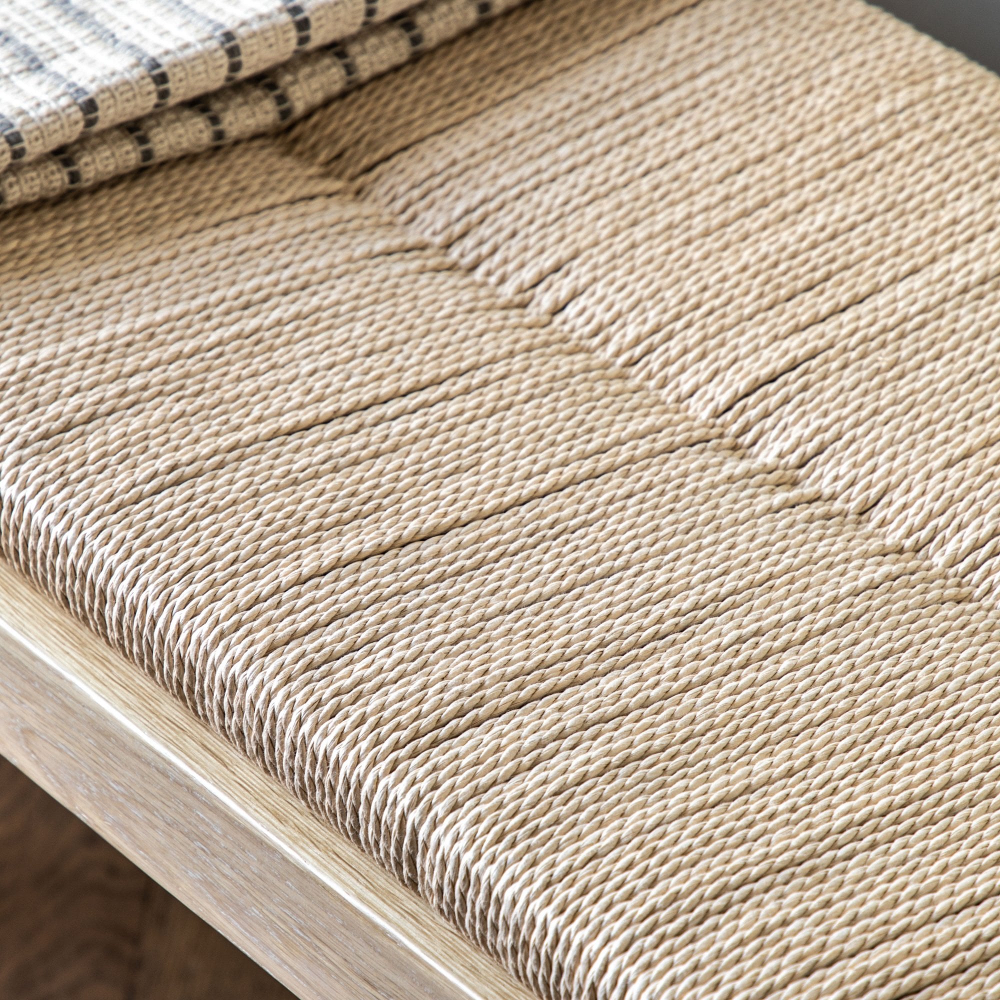 Detailed view of the intricate woven pattern of the bench's natural fiber seat.