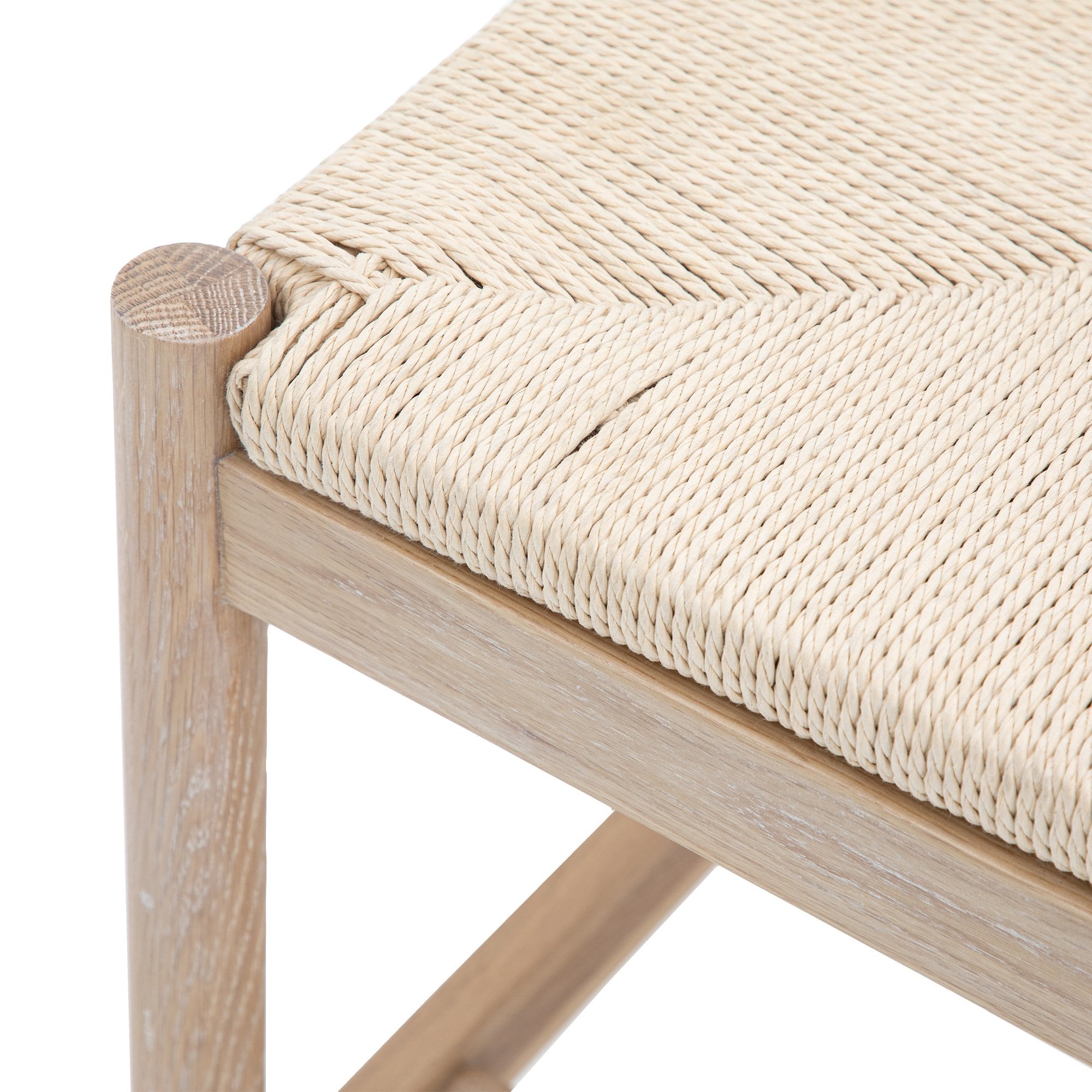 Close-up of the corner of the wooden bench, showing the woven seat and leg joint.
