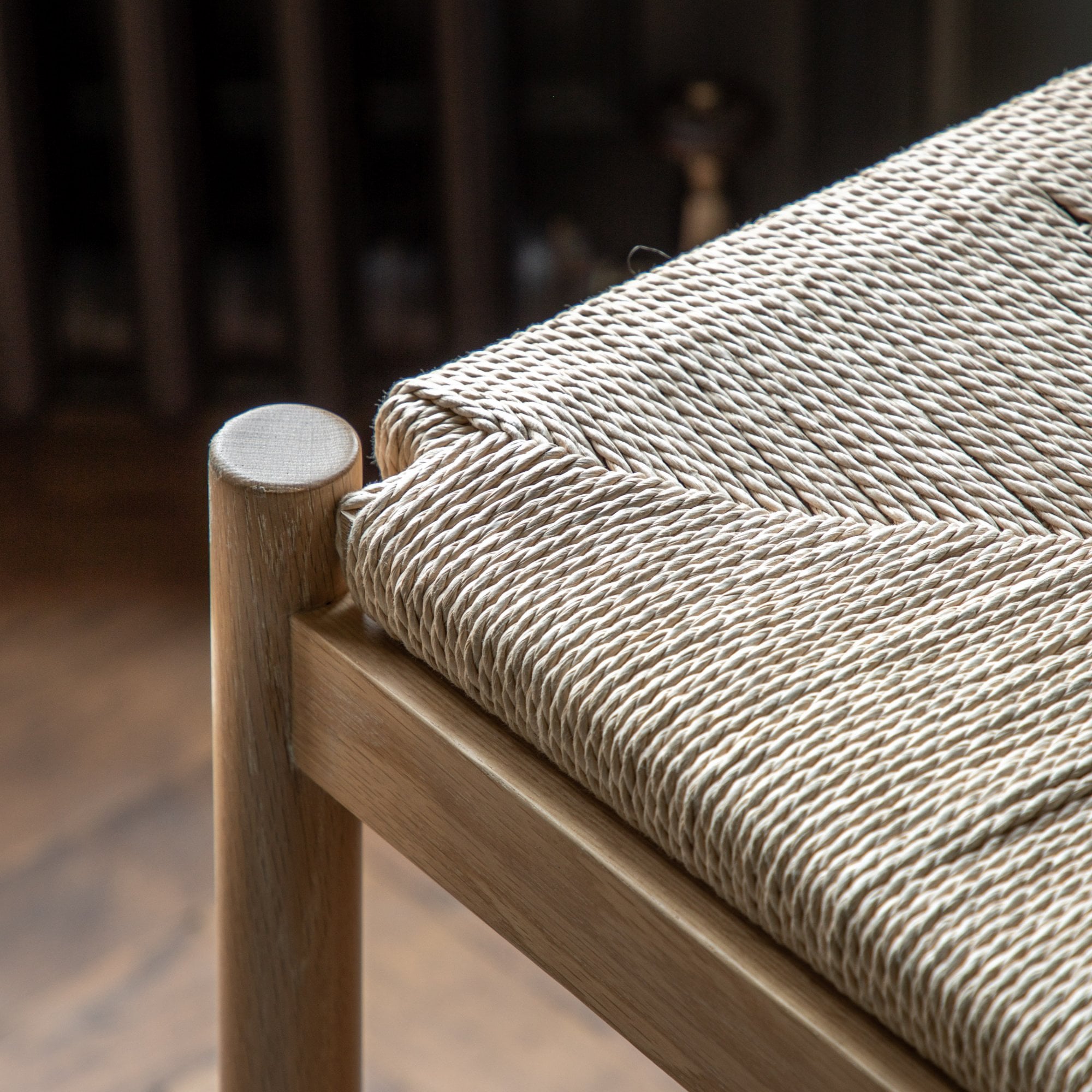 Close-up of the woven seagrass seat and light wood frame of a modern bar stool.