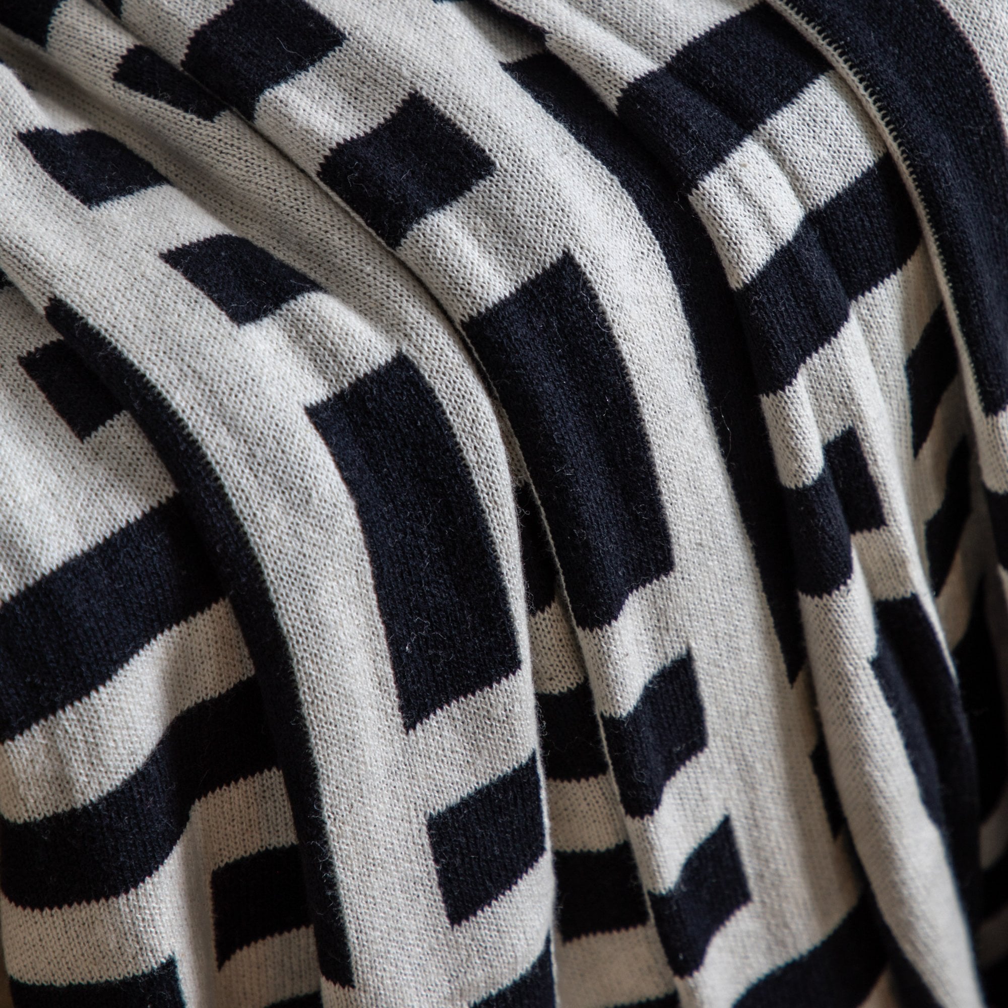 Close-up of a throw with a black and white geometric pattern.