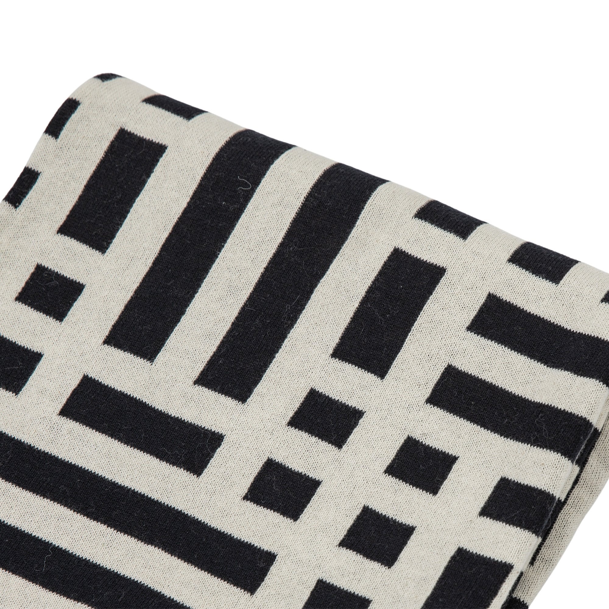 Close-up of a throw with a black and white geometric pattern.