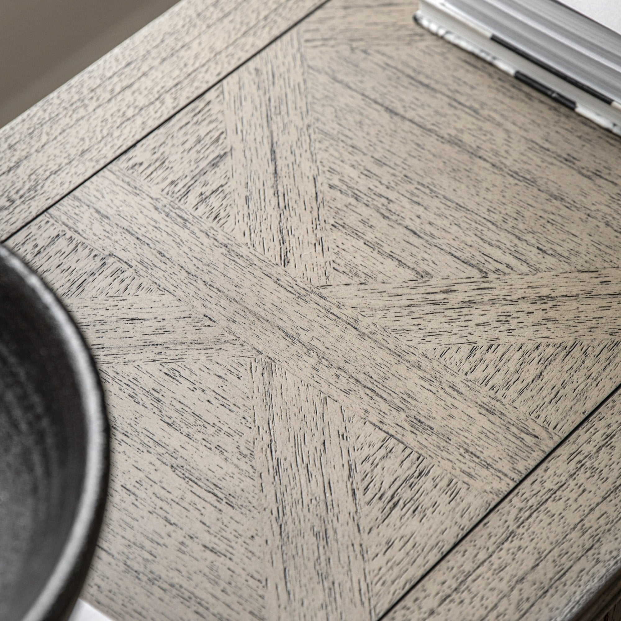 Close-up of the tabletop with a geometric patterned wood grain, a dark bowl, and books.