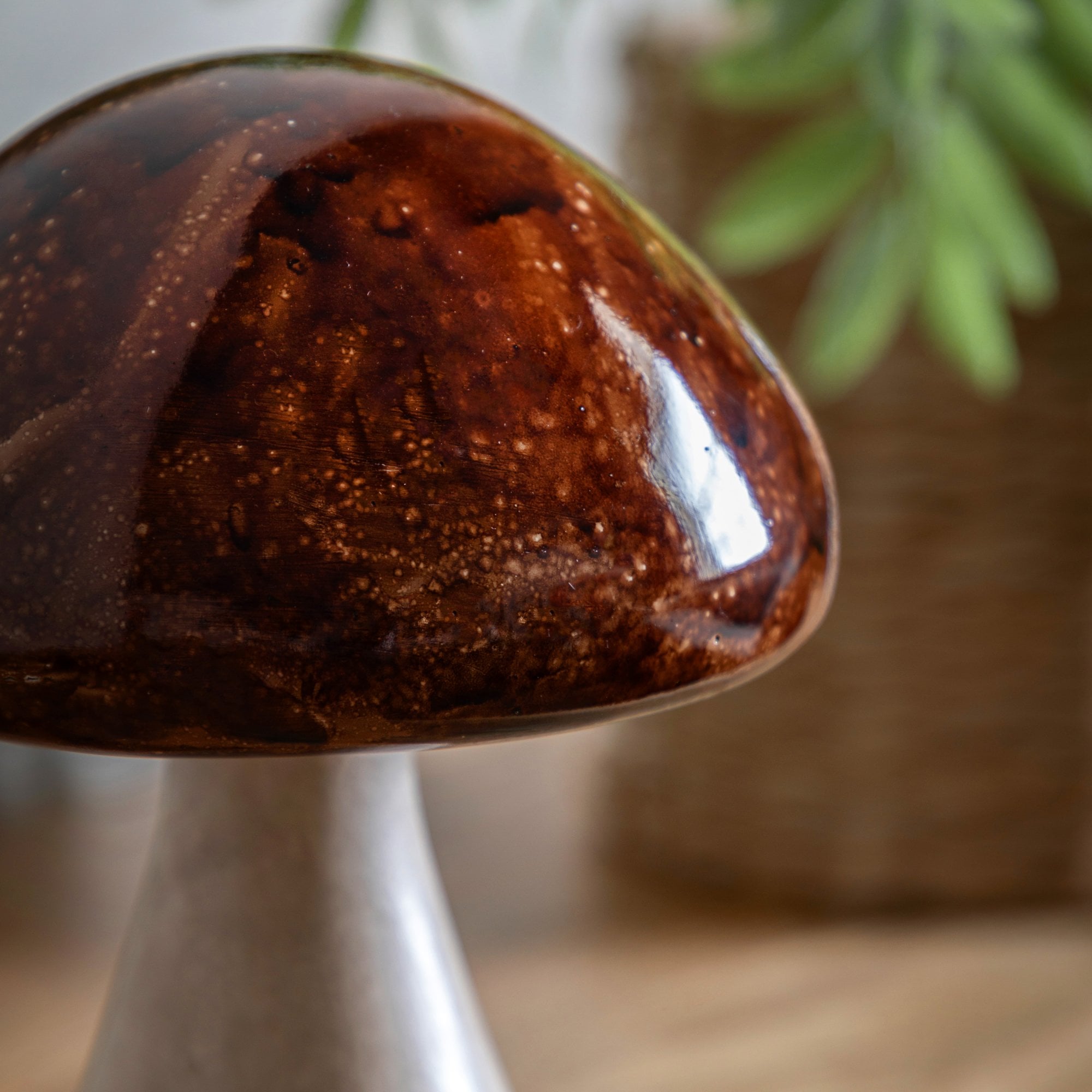 Close-up of a decorative mushroom ornament with a glossy brown cap and cream stem.