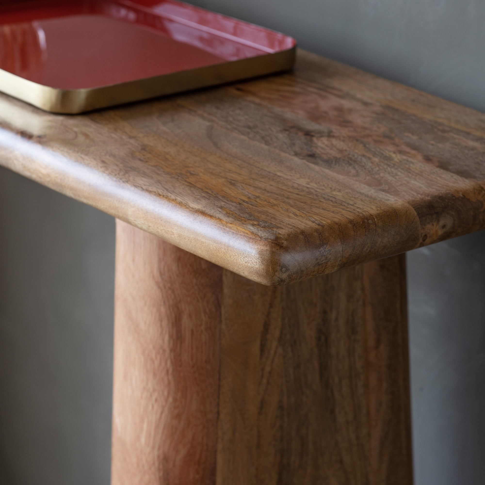 Close-up of a mango wood table surface featuring a red and gold decorative tray.