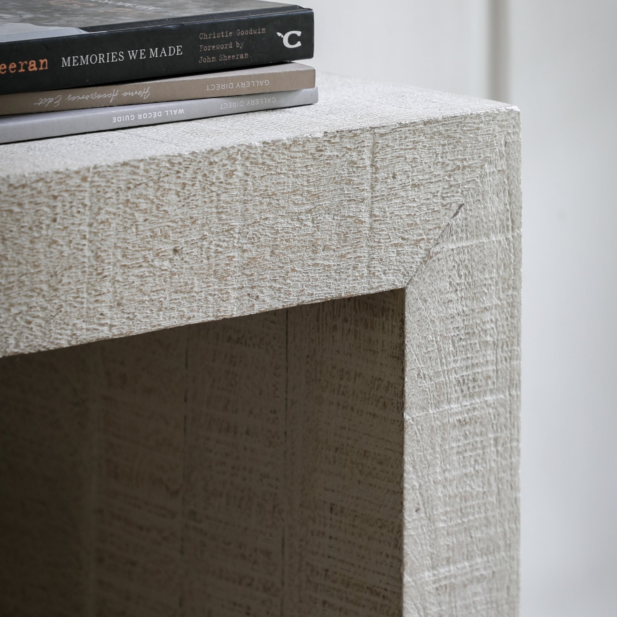 The textured surface of a white console table with books on top.