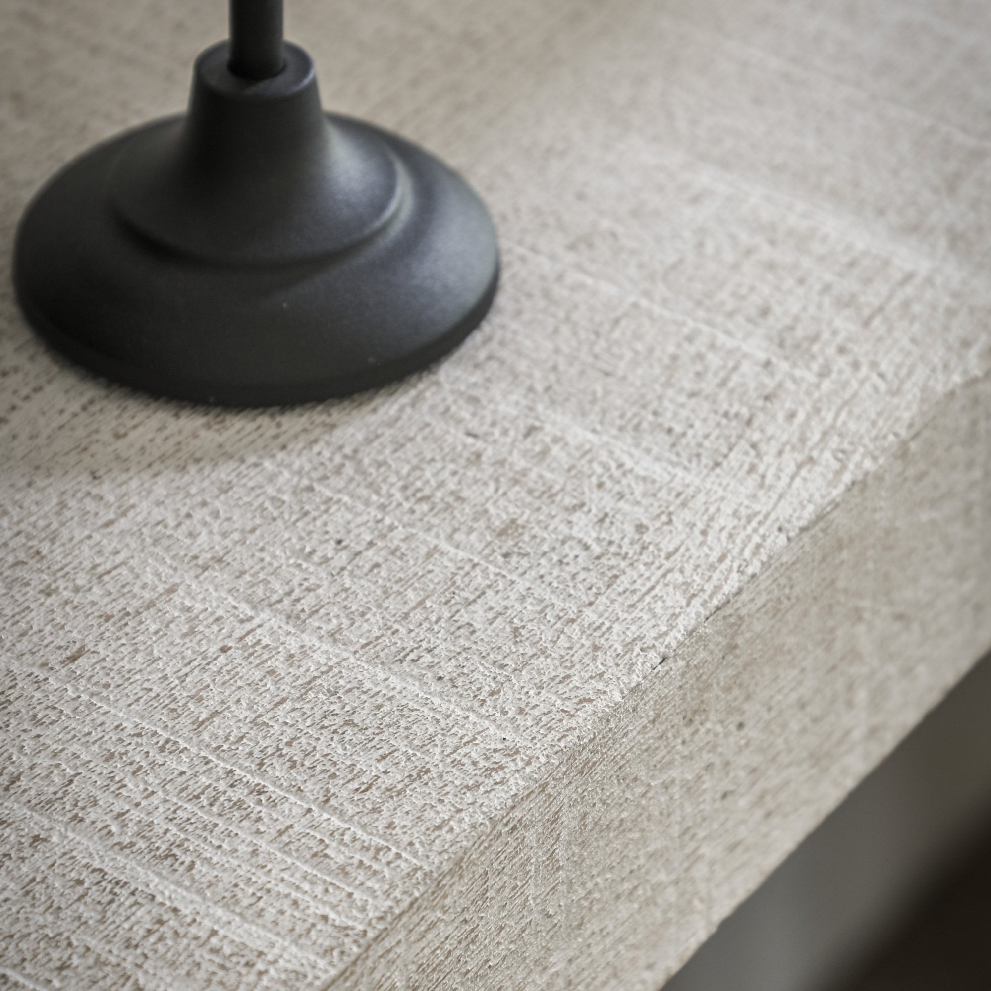 A close-up of the textured surface of a white console table with a black object on it.