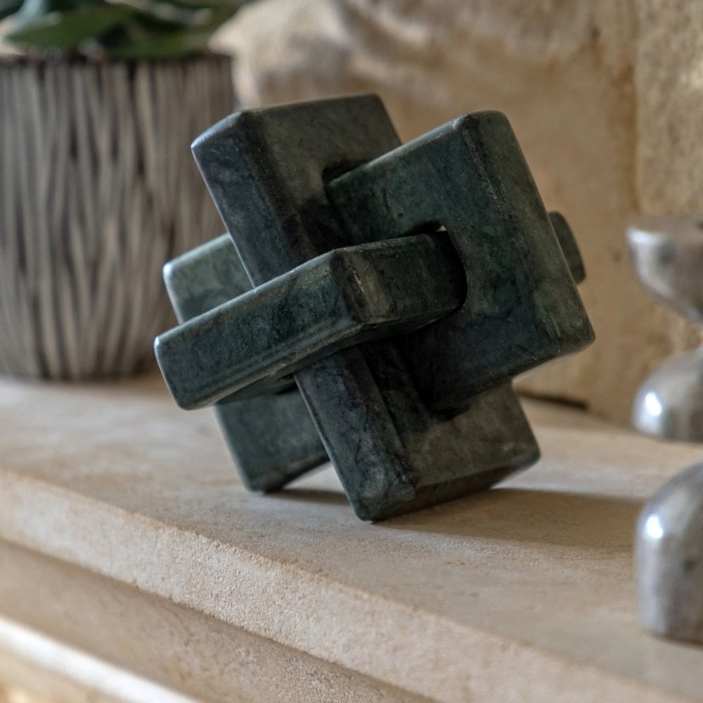 A decorative green knot sculpture on a shelf.