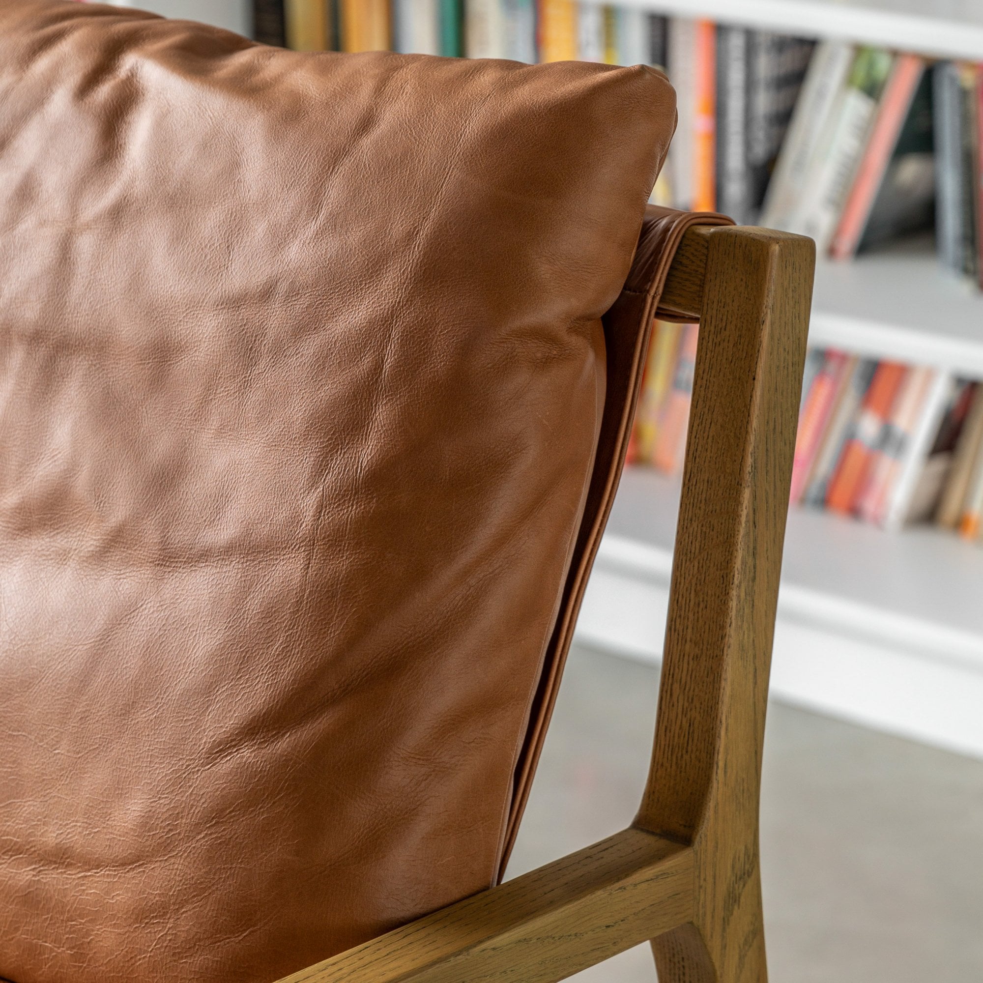 Close-up of the tan leather cushion and wooden frame of an armchair.
