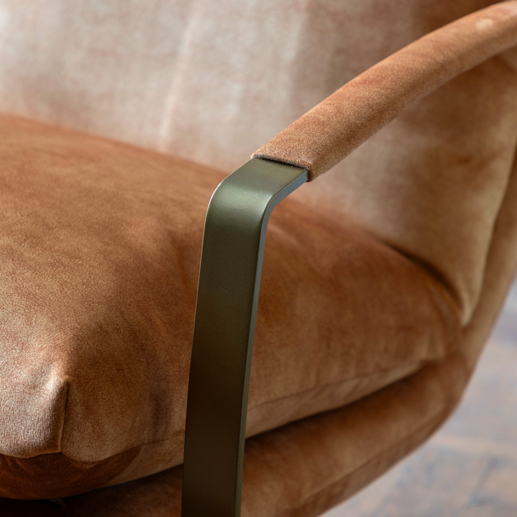 Close-up of the metal armrest and brown upholstered cushion of a lounge chair.