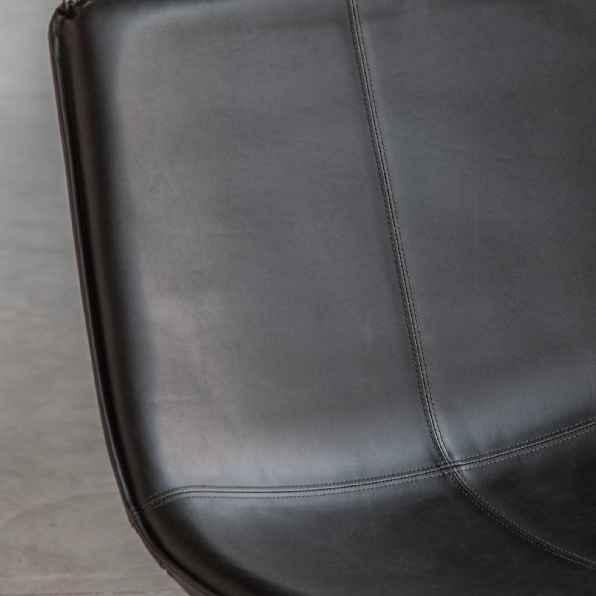 Detailed view of the dark grey leather upholstery and stitching of the chair seat.