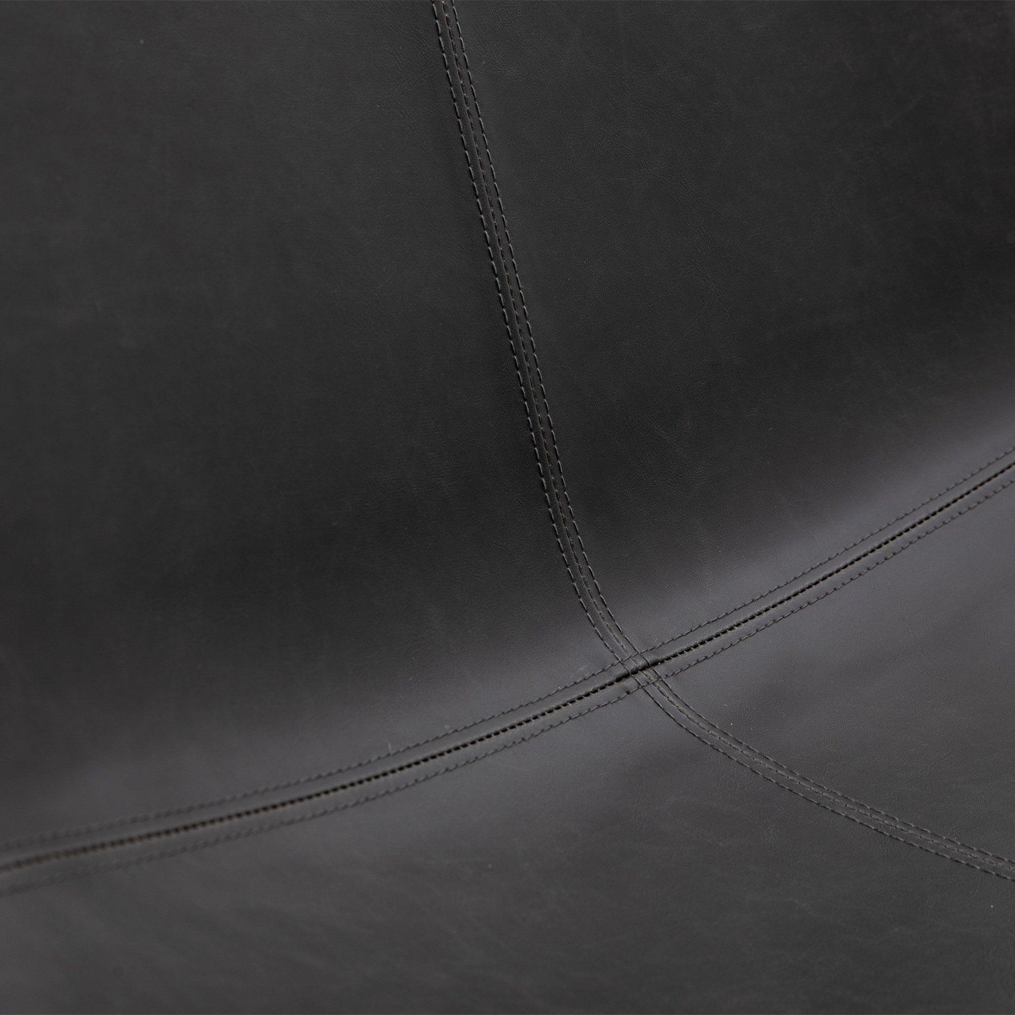 Close-up of the dark grey leather texture and accent stitching on the chair seat.