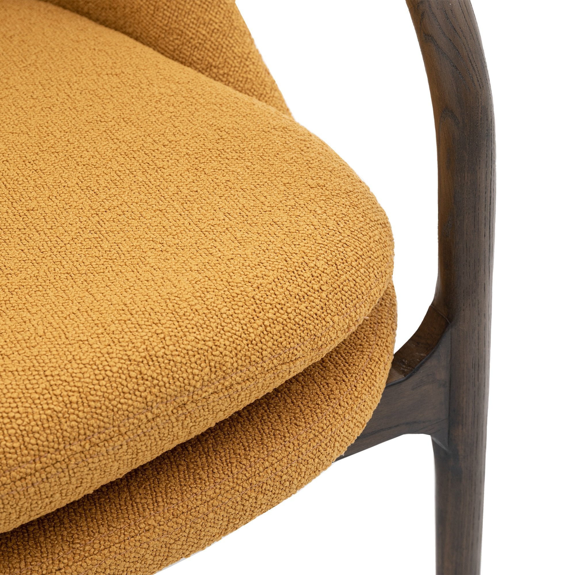 Close-up of the mustard yellow upholstered seat and dark wooden frame detail of an accent chair.