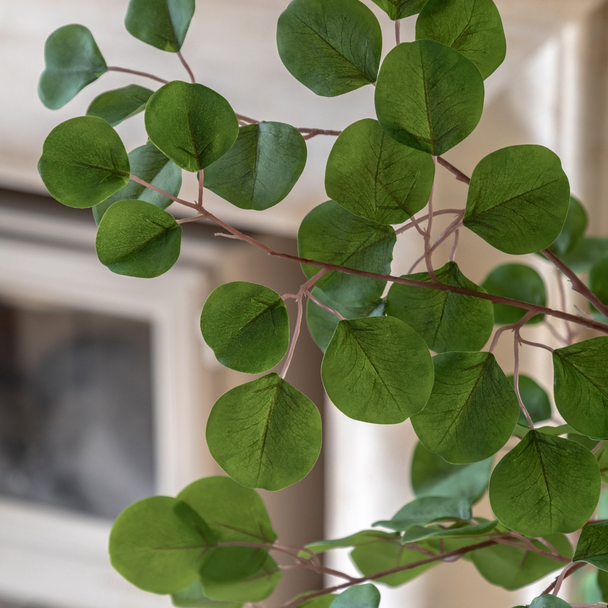 Close-up of the realistic green leaves and delicate branches of a faux eucalyptus tree.