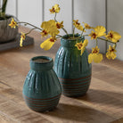 Two blue vases with yellow flowers on a wooden table, adding a pop of color.