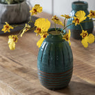 A single blue vase with yellow flowers on a wooden table, enhancing room decor.