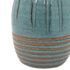 Close-up of the bottom of a blue ceramic vase with textured horizontal lines.