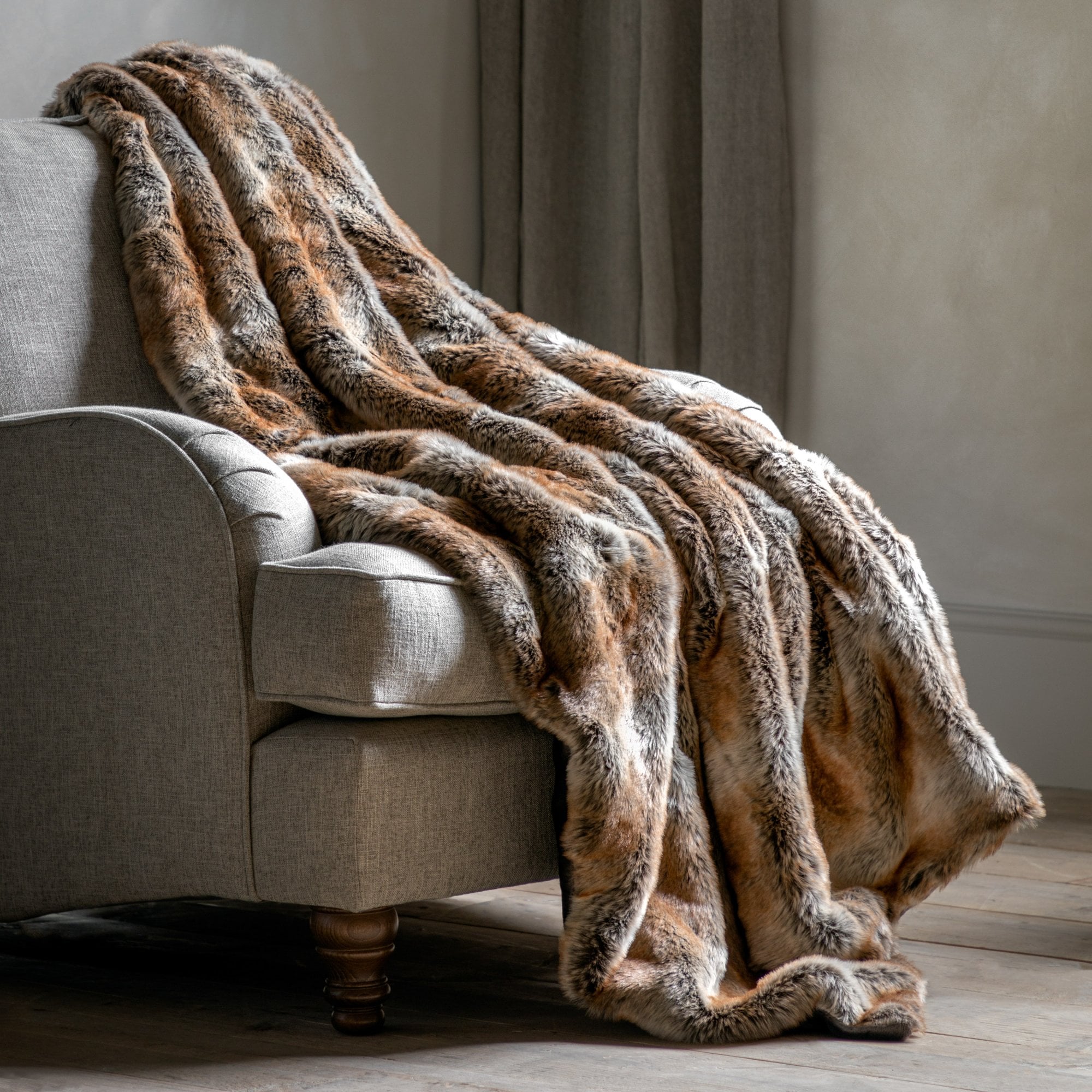 A luxurious brown and cream faux fur throw draped elegantly over an armchair, creating a cozy and inviting look.