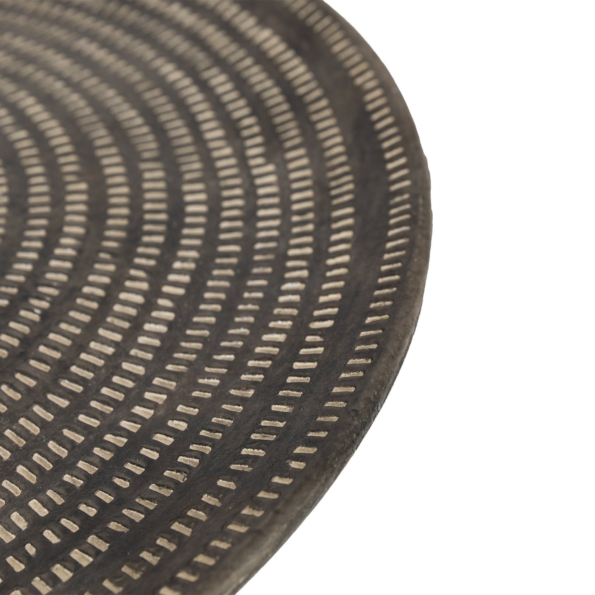 Detailed close-up of a dark-toned decorative tray's surface with carved concentric patterns.