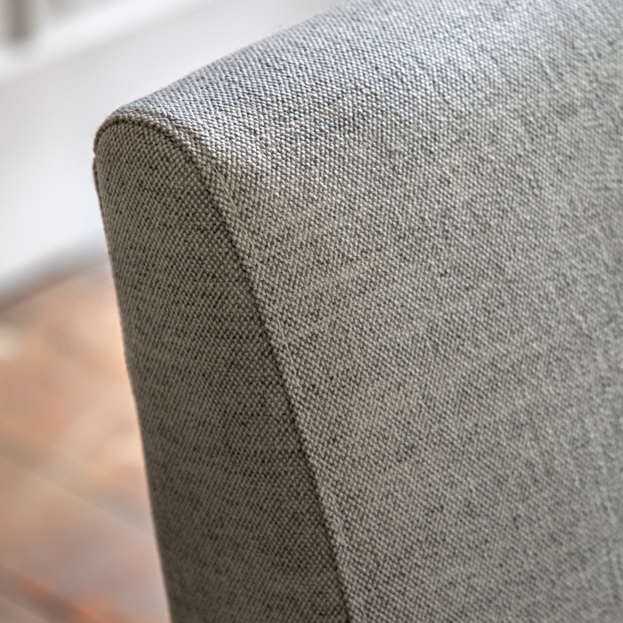 Close-up of the light grey textured fabric upholstery on the back of the armchair.