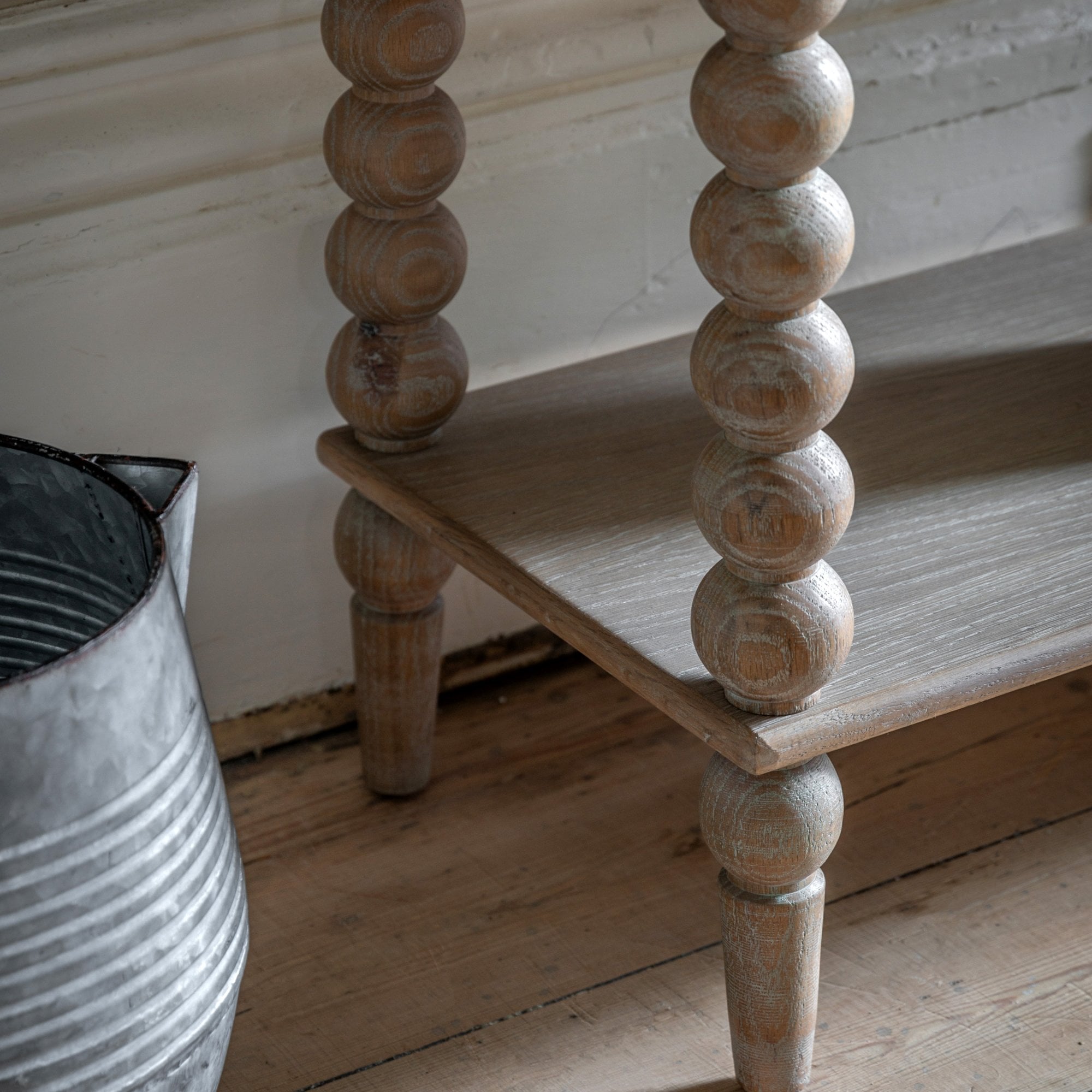 Detail view of the bobbin legs and lower shelf of the light wood console table.