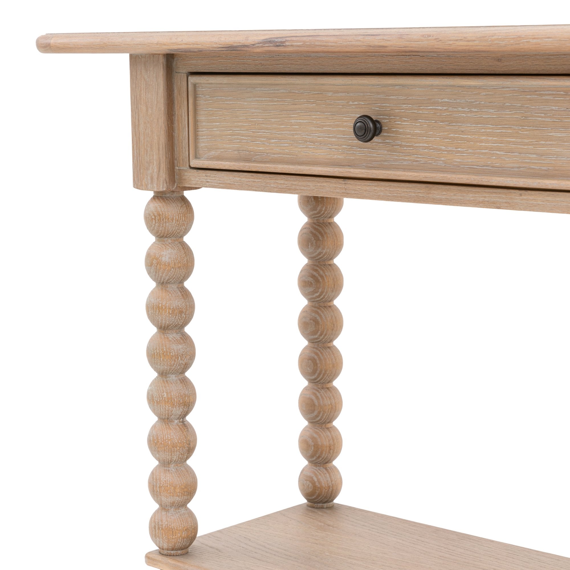Close-up of a drawer with a knob and a bobbin leg on the light wood console table.